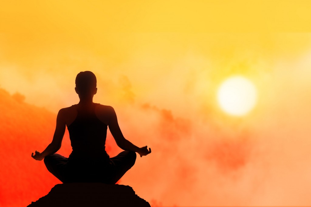 women meditating on high mountain in sunset background