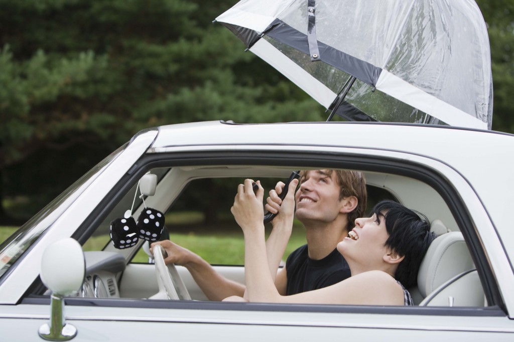 Couple inside car with umbrella out of the sunroof