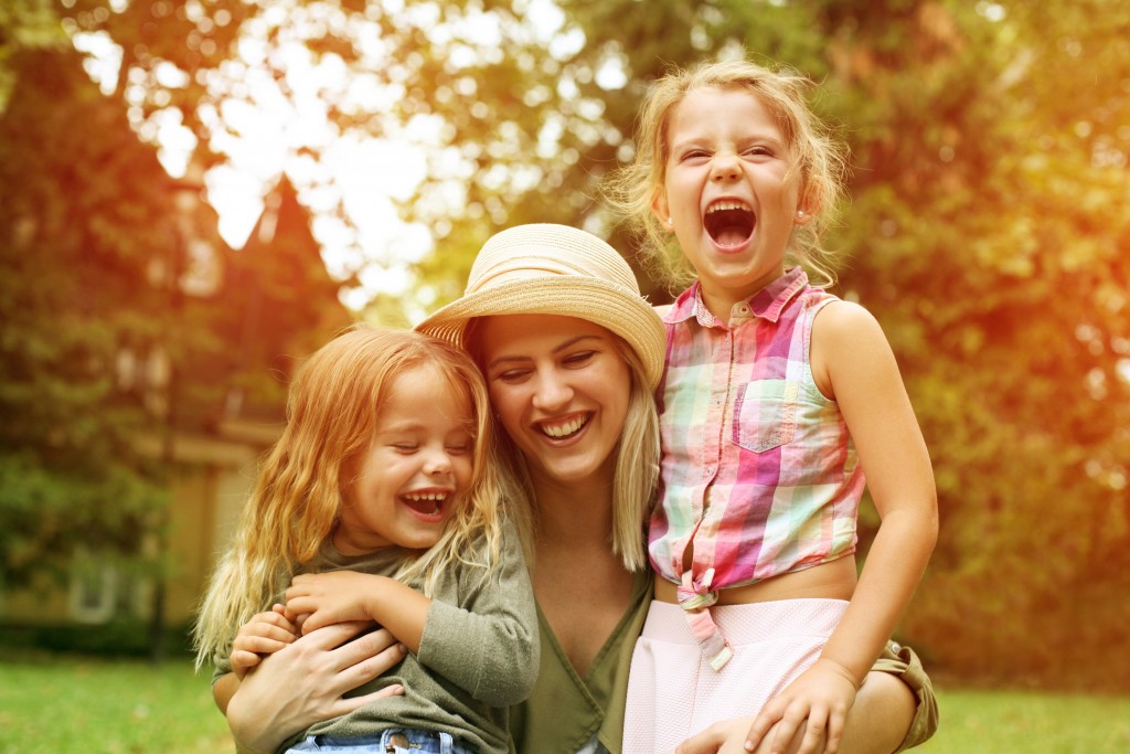 Cheerful mother with her kids having fun outdoor.