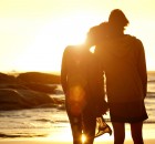 Loving couple holding hands at the beach watching the sunset