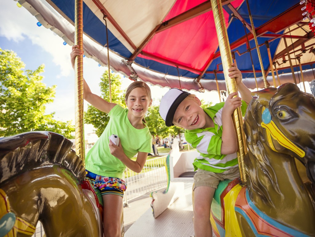 Cute kids having fun riding on a colorful carnival carousel